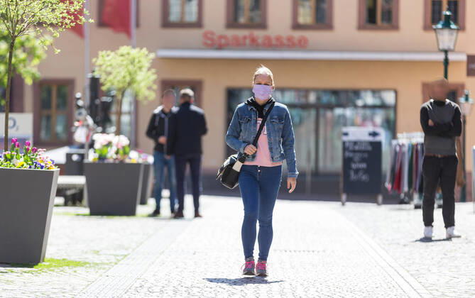 Deutschland, , , 20.04.2020, Presse, COVID-19 Deutschland faehrt langsam wieder hoch Bild: In Hessen haben die Geschaefte wieder geoeffnet, in Bayern nicht. Das wirkt sich vor allem auf die Osthessische Stadt Fulda aus, die nicht weit von der Bayerischen Landesgrenze entfernt liegt. Eine Frau läuft mit Mundschutz durch Fulda. Copyright: HMBxMedia OliverxMueller