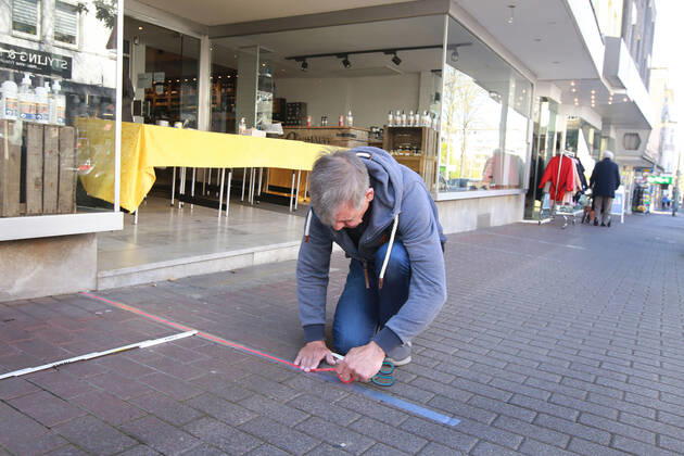 20.04.2020 Dortmund, NRW, Nach mehr als vier Wochern des Shut Downs sind heute die ersten Lockerungen für die Geschäfts angelaufen. Läden mit bis zu 800 Quadratmetern Verkaufsfläche dürfen wieder öffnen. Abstandsregeln und Hygienemaßnahmen müssen weiter eingehalten werden. Viele Kunden nutzten diese Lockerungen und gingen einkaufen. Ein Geschäftsinhaber klebt Abstandszonen vor seinem Ladenlokal ab. Er wird nur über den Tisch im Eingang verkaufen. Er möchte verhindert , dass die Kunden seine Waren beim Aussuchen anfassen.