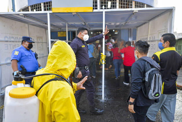 April 20, 2020, San Salvador, El Salvador: A police officer and a sanitization worker explain people how to go thru a sanitization tunnel that sprays chemicals before entering a market..A partial lockdown was placed in the cityÃ‚Â s downtown area. Soldiers and police officer have set dozens of control point to ensure people comply with the measures..El Salvador reports 218 cases and 7 deaths due to the novel Coronavirus. San Salvador El Salvador - ZUMAf143 20200420_zip_f143_004 Copyright: xCamiloxFreedmanx