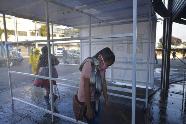April 20, 2020, San Salvador, El Salvador: A woman is sprayed while going thru a sanitization tunnel..A partial lockdown was placed in the cityÃ‚Â s downtown area. Soldiers and police officer have set dozens of control point to ensure people comply with the measures..El Salvador reports 218 cases and 7 deaths due to the novel Coronavirus. San Salvador El Salvador - ZUMAf143 20200420_zip_f143_007 Copyright: xCamiloxFreedmanx