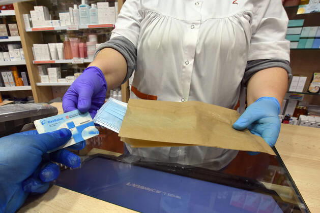 April 20, 2020, Vendrell, Spain: A man shows a Catalan health card to a pharmacist in order to receive a free mask provided by the Government of Catalonia in a pharmacy..The pharmacies of Catalonia (Spain) today began to distribute surgical masks to prevent further contagion due to the Covid-19 health crisis that the Government of Catalonia sends to the population. Each citizen is assigned a free mask that is validated with their health cards and if they need a second one the citizen will have to pay for it. Vendrell Spain - ZUMAs197 20200420_zaa_s197_050 Copyright: xRamonxCostax