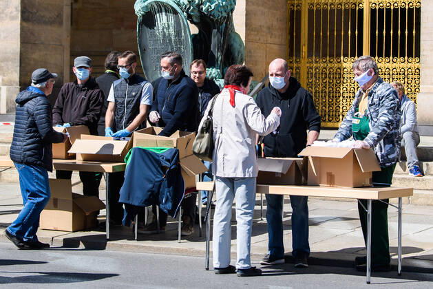 (200420) -- DRESDEN (GERMANY), April 20, 2020 (Xinhua) -- Staff members offer face masks to people in front of the City Hall of Dresden, Saxony state, eastern Germany, on April 20, 2020. The rate of new infections with COVID-19 in Germany continued to fall as the number of confirmed cases only increased by 1,775 within one day to almost 142,000, the Robert Koch Institute (RKI) announced on Monday. (Photo by Kevin Voigt Xinhua) GERMANY-DRESDEN-COVID-19-MEASURES 