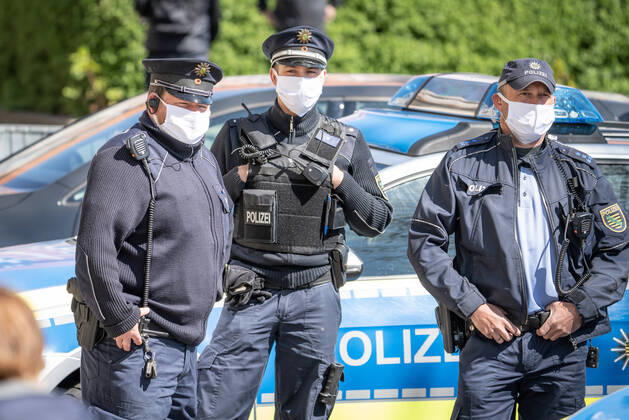Polizisten mit Gesichtsmasken Polizisten mit Gesichtsmasken stehen vor dem Rathaus in Dresden. Tausende Dresdner haben am Montagmorgen vor dem Dresdner Rathaus für eine kostenlose Schutzmaske Schlange gestanden. Über mehrere hundert Meter standen die Bürger bis hin zur Goldenen Pforte, wo nach Angaben der Stadt rund 20 000 Mund-Nasenbedeckungen aus Stoff in den Farben schwarz oder weiß verteilt wurden. Pro Person wurde eine Maske ausgegeben - eine weitere durfte für Familienmitglieder mitgenommen werden. Insgesamt hat Oberbürgermeister Dirk Hilbert (FDP) rund 200 000 Masken geordert, die in den nächsten Tagen dezentral an Einwohner der Stadt verteilt werden sollen. Der Mund- und Nasenschutz stammt aus der Produktion von Dresdner Firmen. Seit Montag müssen Sachsen beim Einkaufen sowie in Bussen und Bahnen einen Mund- und Nasensch