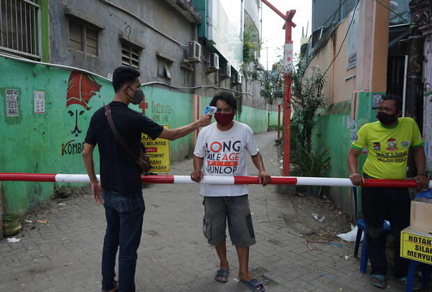 Indonesia: Lockdown to prevent from Covid-19 Residents in the settlements do a local lockdown of their area and forbid anyone who is not a local citizen to enter their area without any reason. In front of the gate, there is an iron bar and guarded by residents for 24 hours. Everyone who entered was checked for body temperature and anti-septic spray in an effort to prevent the spread of the Covid-19 outbreak in their area. Makassar South Sulawesi Indonesia Copyright: HerwinxBahar