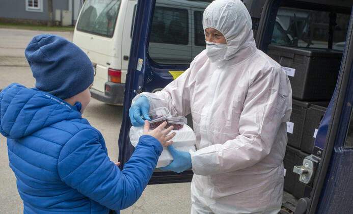 (200421) -- OGRE, April 21, 2020 (Xinhua) -- A staff member distributes free food to a child from low-income household in Ogre, Latvia, April 20, 2020. Latvia has prolonged the state of emergency till May 12. (Photo by Janis Xinhua) LATVIA-OGRE-COVID-19-FOOD DISTRIBUTION 
