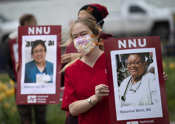 Nurses hold photos of fellow healthcare workers who have died from COVID-19 during a protest calling attention on healthcare infections nationwide and demanding the Trump administration to provide extra PPE for healthcare workers during the coronavirus pandemic, at the White House in Washington, D.C. on Tuesday, April 21, 2020.  WAP20200421320 KEVINxDIETSCH