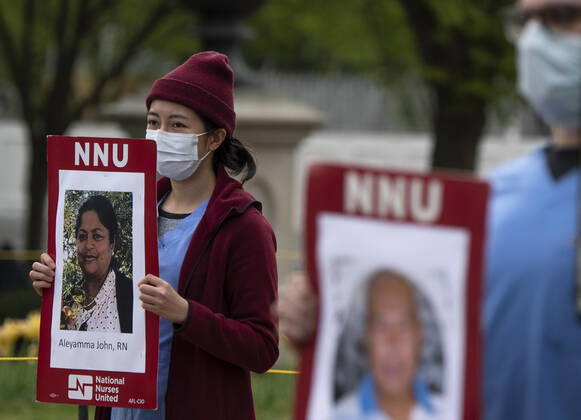 Nurses hold photos of fellow healthcare workers who have died from COVID-19 during a protest calling attention on healthcare infections nationwide and demanding the Trump administration to provide extra PPE for healthcare workers during the coronavirus pandemic, at the White House in Washington, D.C. on Tuesday, April 21, 2020.  WAP20200421323 KEVINxDIETSCH