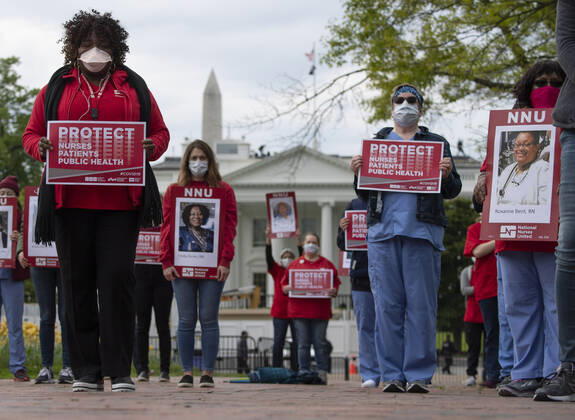 Nurses hold photos of fellow healthcare workers who have died from COVID-19 during a protest calling attention on healthcare infections nationwide and demanding the Trump administration to provide extra PPE for healthcare workers during the coronavirus pandemic, at the White House in Washington, D.C. on Tuesday, April 21, 2020.  WAP20200421321 KEVINxDIETSCH