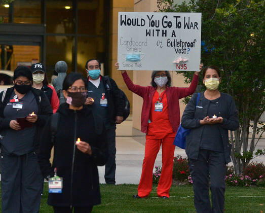 Registered nurses at the UC Irvine Medical Center hold a candlelight vigil after their shift change to call attention to healthcare workers nationwide who have been infected with COVID-19 and demanding the Trump administration provide N95 masks and extra PPE for healthcare workers during the coronavirus pandemic in Irvine, California on Monday, April 20, 2020.  LAP2020042005 JIMxRUYMEN