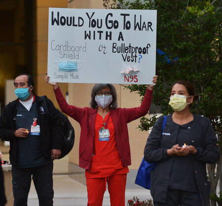 Registered nurses at the UC Irvine Medical Center hold a candlelight vigil after their shift change to call attention to healthcare workers nationwide who have been infected with COVID-19 and demanding the Trump administration provide N95 masks and extra PPE for healthcare workers during the coronavirus pandemic in Irvine, California on Monday, April 20, 2020.  LAP2020042006 JIMxRUYMEN