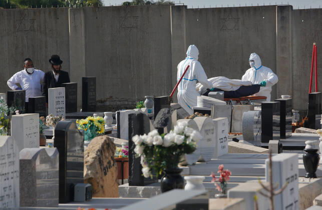 (200421) -- REHOVOT (ISRAEL), April 21, 2020 (Xinhua) -- Funeral workers wearing masks and protective gear carry the body of a patient who died from COVID-19 at a cemetery in central Israeli city of Rehovot, on April 21, 2020. Israel s Ministry of Health reported 229 new cases on Tuesday, bringing the total infections to 13,942. (Photo by Gil Cohen Magen Xinhua) ISRAEL-REHOVOT-COVID-19-FUNERAL 
