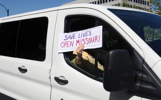 A sign favoring to open Missouri is displayed as cars sound their horns, driving by the St. Louis County Government Center, during a drive-by protest in Clayton, Missouri on Tuesday, April 21, 2020. The people driving around the block plus those with signs, cheering on the sidewalks are protesting the fact that Missouri businesses are closed due to the coronavirus pandemic.  SLP2020042109 BILLxGREENBLATT