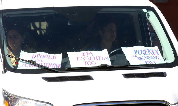 Drivers sound their horns, driving by the St. Louis County Government Center, with messages on their dashboard during a drive-by protest in Clayton, Missouri on Tuesday, April 21, 2020. The people driving around the block plus those with signs, cheering on the sidewalks are protesting the fact that Missouri businesses are closed due to the coronavirus pandemic.  SLP2020042118 BILLxGREENBLATT