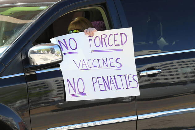 People hold signs outside of their vehicles as they sound their horns, driving by the St. Louis County Government Center, during a drive-by protest in Clayton, Missouri on Tuesday, April 21, 2020. The people driving around the block plus those with signs, cheering on the sidewalks are protesting the fact that Missouri businesses are closed due to the coronavirus pandemic.  SLP2020042119 BILLxGREENBLATT