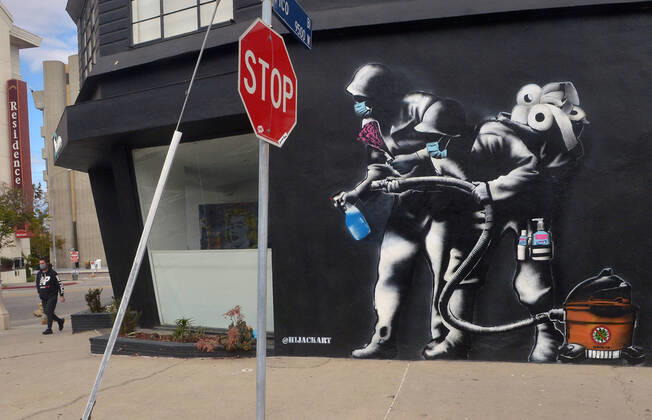 In this mural, a duo goes COVID-19 busting, armed with hand sanitizer, a vacuum cleaner, and lots of toilet paper in Los Angeles on Sunday, April 19, 2020. Illustrated by local artist Hijack, the mural depicts two-soldiers fending off the coronavirus wearing Hazmat suits with a feather duster, Windex, hand sanitizer and a vacuum bearing a No Covid-19 symbol. Hijack said, I m being told it feels like we re in wartime, so I also wanted to add that element to the piece.  LAP2020042110 JIMxRUYMEN