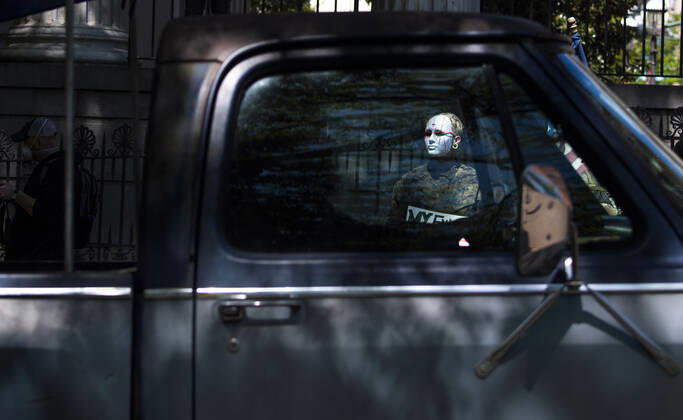 A protester is seen through the widow of a car during a rally calling on Gov. Ralph Northam to reopen Virginia and end executive order 53 with bans gatherings of over 10 in the midst of the Coronavirus COVID-19 pandemic, near the State Capitol Building in Richmond, Virginia on Wednesday, April 22, 2020. The group is urging the reopening of business despite the COVID-19 pandemic still infecting the nation.  WAP20200422317 KEVINxDIETSCH