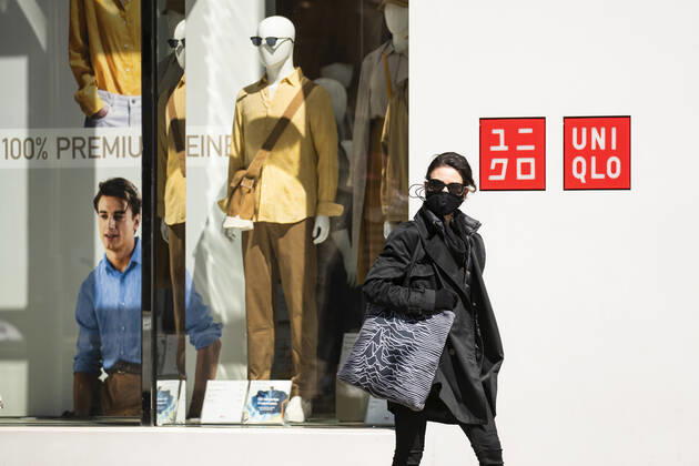 Menschen mit Mundschutzmaske vor einer Vitrine von Uniqlo in Berlin am 22. April 2020. Ab heute koennen in Berlin laeden unter 800 qm, Buchhandlucngen und Autosalons wieder oeffnen mit Einhanltung von Hygiene und Distanzvorschriften. Coronavirus in Berlin
