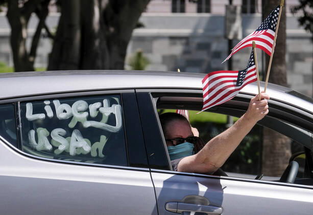 April 22, 2020, Los Angeles, California, U.S: A demonstrator in a car waves U.S. flags during a vehicle caravan protest to call on state and local officials to re-open the economy during the coronavirus disease outbreak in downtown Los Angeles, Wednesday April 22, 2020. Los Angeles U.S. - ZUMAc68_ 20200422_zaf_c68_018 Copyright: xRingoxChiux