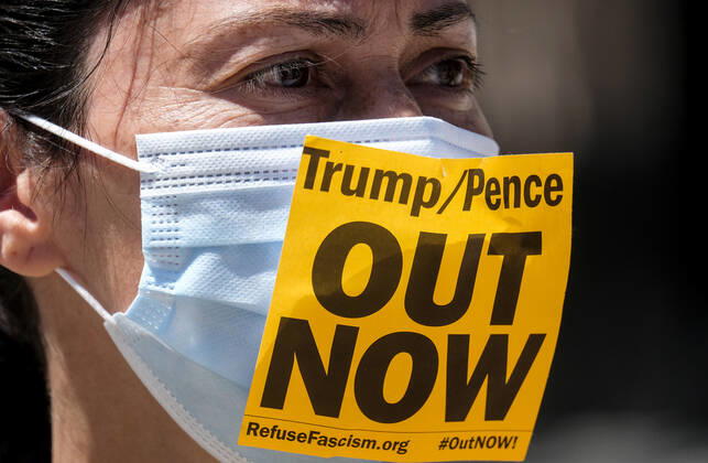 April 22, 2020, Los Angeles, California, U.S: A counter demonstrator wearing a face mask with a sign takes part a vehicle caravan protest to call on state and local officials to re-open the economy during the coronavirus disease outbreak in downtown Los Angeles, Wednesday April 22, 2020. Los Angeles U.S. - ZUMAc68_ 20200422_zaf_c68_034 Copyright: xRingoxChiux