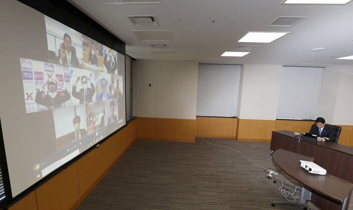 New coronavirus Japanese economic revitalization minister Yasutoshi Nishimura (R) takes part in a videoconference with a group of governors from around the country to discuss measures against the new coronavirus on April 23, 2020, in Tokyo. 