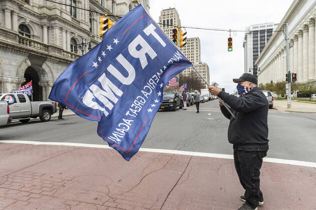 NY: Operation Gridlock in Albany A man wearing facial bandana holds Trump 2020 flag and participates in Operation Gridlock protest outside of New York State Capitol Building. Participants demanded reopening of New York State. Many people on the street disregarded wearing facial masks and keep social distances. Albany New York United States Copyright: LevxRadin
