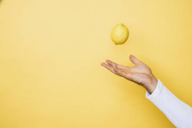 Studio shot of hand of person tossing up lemon model released Symbolfoto DAWF01394