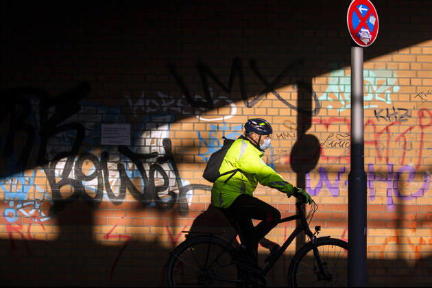 Ein Radfahrer mit Mundschutzmaske in Berlin am 23. April 2020. Ab gestern koennen laeden unter 800 qm, Buchhandlucngen und Autosalons wieder oeffnen mit Einhanltung von Hygiene und Distanzvorschriften. Heute waren spuerbar mehr Menschen unterwegs. Coronavirus in Berlin
