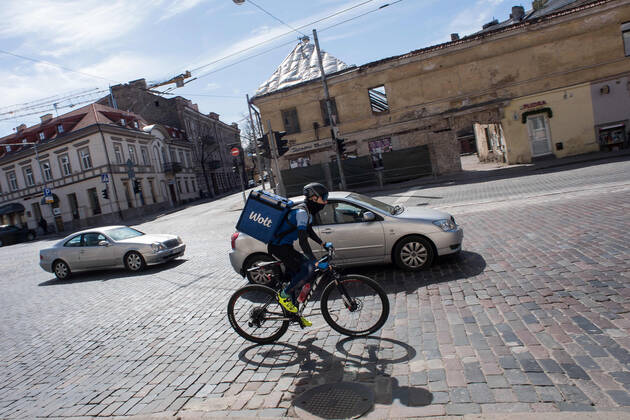 Coronavirus in Litauen, Eindrücke aus Vilnius (200424) -- VILNIUS, April 24, 2020 (Xinhua) -- A deliveryman wearing a mask rides a bicycle in the old town of Vilnius, capital of Lithuania, April 23, 2020. The government of Lithuania on Wednesday extended the nationwide quarantine restrictions until May 11 with the easing measures such as reopening of all shops and shopping malls from Thursday. Th new measures also included letting outdoor cafes, hairdressing, beauty parlors, libraries and museums to resume operation from the start of the next week. (Photo by Alfredas Pliadis Xinhua) LITHUANIA-VILNIUS-COVID-19 