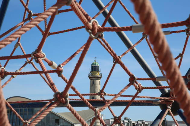 Nichts geht mehr am Meer: Blick am Donnerstag (23.04.2020) auf das fast leere Ostseebad Warnemünde. Die Urlaubsregionen des Landes Mecklenburg Vorpommern sind infolge der Corona Krise nach wie vor für Touristen gesperrt. Das wirkt sich mehr und mehr auf die wirtschaftliche Bilanz der Tourismuswirtschaft aus. So fehlen unter anderem die Einnahmen aus der Kurtaxe, den Parkgebühren, den Gaststätten und der Fahrgastschifffahrt. Das nagt bei einigen Unternehmen bereits an der Existenz. Denn die Einheimischen können die Einnahmen aus dem Tourismus nicht auffangen. Das zeigte sich insbesondere auch im Verlauf des Tages in dem Urlaubsort an der Ostseeküste. Dort waren nur wenige Menschen auf den Straßen unterwegs. Im Bild der historische Leuchtturm mit einem Spielgerät im Vordergrund