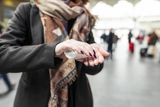 Woman using sanitising hand gel at train station model released Symbolfoto WPEF02797