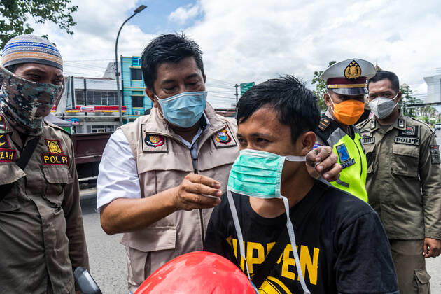 Coronavirus in Indonesien, Eindrücke aus Makasar April 24, 2020, Makassar, South Sulawesi, Indonesia: Police officers put masks on a motorbike driver who did not wear a mask when crossing the border in Makassar City, South Sulawesi Province, Makassar, Indonesia, to prevent Covid-19 transmission. Every citizen who does not wear a mask will be stopped and asked to return home. The curbing was carried out after the implementation of large-scale social restrictions in Makassar City and because the Covid-19 outbreak continued to increase in Indonesia. Makassar Indonesia - ZUMAb223 20200424_zip_b223_011 Copyright: xHerwinxBaharx
