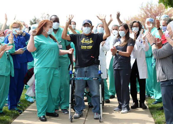 St. Louis Metropolitan motorcycle Police Officer Dave Tenorio stands and puts his hands up as he takes a walker, during a celebration discharge, at St. Luke s Hospital, in Chesterfield, Missouri on Friday, April 24, 2020. After being admitted on April 1,Tenorio is St. Luke s first COVID-19 patient to be treated with ECMO (extracorporeal membrane oxygenation) and is the first known COVID-19 patient in the St. Louis region to be treated with ECMO and be released. ECMO acts as an outside heart and lung to support the body when a person?s own organs are too sick to do the job. It extracts blood, adds oxygen and pumps blood back into the body.  SLP2020042407 BILLxGREENBLATT
