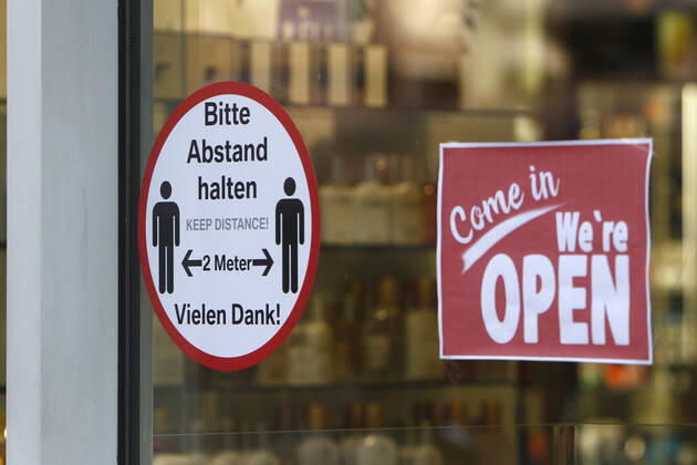 Sicherheitshinweis zur Abstandswahrung von zwei Metern und Schild wir haben geöffnet an der Tür zu einem Geschäft in der Innenstadt von Frankfurt, Hessen, Deutschland