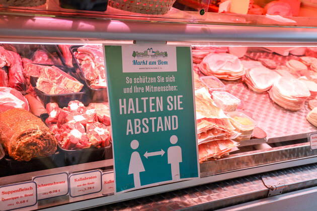 DEU, Deutschland, Nordrhein-Westfalen, Münster, 25.04.2020: Einkaufen auf dem Wochenmarkt - wegen der Corona Ansteckungsgefahr wurde der Wochenmarkt entzerrt, damit zwischen Ständen Freiflächen für wartende Kunden entstehen. Neben dem Domplatz stehen einige Marktstände am Prinzipalmarkt, Auch am Michaelisplatz werden Stände aufgebaut. Schild Halten Sie Abstand