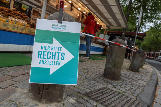 DEU, Deutschland, Nordrhein-Westfalen, Münster, 25.04.2020: Einkaufen auf dem Wochenmarkt - wegen der Corona Ansteckungsgefahr wurde der Wochenmarkt entzerrt, damit zwischen Ständen Freiflächen für wartende Kunden entstehen. Neben dem Domplatz stehen einige Marktstände am Prinzipalmarkt, Auch am Michaelisplatz werden Stände aufgebaut. Schild Hier bitte rechts anstellen