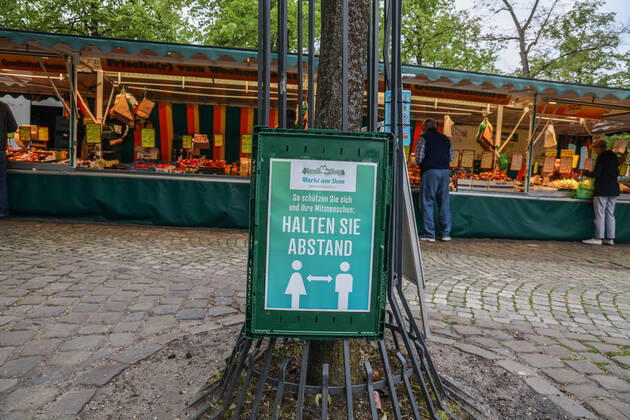 DEU, Deutschland, Nordrhein-Westfalen, Münster, 25.04.2020: Einkaufen auf dem Wochenmarkt - wegen der Corona Ansteckungsgefahr wurde der Wochenmarkt entzerrt, damit zwischen Ständen Freiflächen für wartende Kunden entstehen. Neben dem Domplatz stehen einige Marktstände am Prinzipalmarkt, Auch am Michaelisplatz werden Stände aufgebaut. Schild Halten Sie Abstand