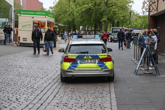 DEU, Deutschland, Nordrhein-Westfalen, Münster, 25.04.2020: Einkaufen auf dem Wochenmarkt - wegen der Corona Ansteckungsgefahr wurde der Wochenmarkt entzerrt, damit zwischen Ständen Freiflächen für wartende Kunden entstehen. Neben dem Domplatz stehen einige Marktstände am Prinzipalmarkt, Auch am Michaelisplatz werden Stände aufgebaut. Polizeistreife vom Polizeiauto auf dem Wochenmarkt