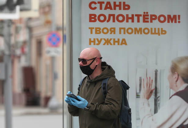 MOSCOW, RUSSIA - APRIL 25, 2020: A man in a face mask and gloves with a mobile phone stands at a bus stop in central Moscow during the pandemic of the novel coronavirus disease (COVID-19). The message on the poster reads: Be a Volunteer! We Need Your Help! Since 30 March, Moscow has been on lockdown. Earlier, the Russian government announced a paid period off work for employed people, which has been extended till the end of April. As of 25 April 2020, Russia has reported more than 68,700 confirmed cases of the novel coronavirus infection, with more than 36,800 confirmed cases in Moscow. Vladimir Gerdo TASS  TS0D7091