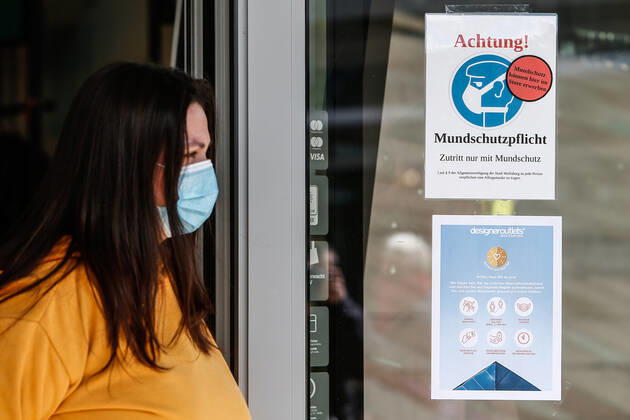 25.04.2020, xtgx, Folgen des Corona Virus in Wolfsburg, eine Mitarbeiterin steht mit Schutzmaske vor einem Hinweisschild im Designer Outlet Wolfsburg (DOW, Outlet Center). In Wolfsburg gilt eine Pflicht, in allen Geschaeften und in Bussen eine Maske zu tragen, die Mund und Nase bedeckt. Wolfsburg