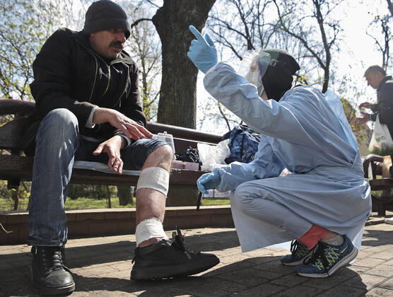 MINSK, BELARUS - APRIL 25, 2020: A volunteer provides medical care to a homeless man in Minsk s Mikhailovsky Garden Square. Natalia Fedosenko TASS  TS0D7102