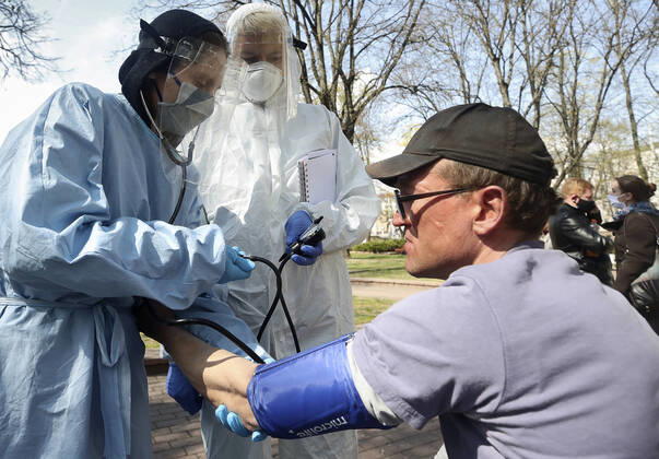 MINSK, BELARUS - APRIL 25, 2020: Volunteers check a homeless man s blood pressure in Minsk s Mikhailovsky Garden Square. Natalia Fedosenko TASS  TS0D7103