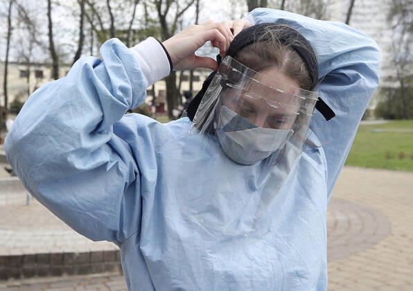 MINSK, BELARUS - APRIL 25, 2020: A volunteer puts on a face shield before providing medical care to a homeless woman in Minsk s Mikhailovsky Garden Square. Natalia Fedosenko TASS  TS0D7106