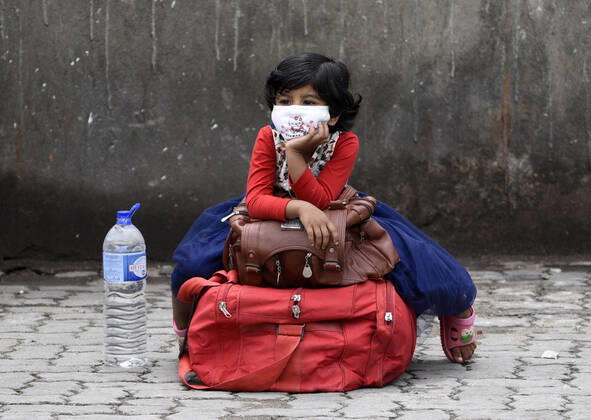 April 25, 2020, Guwahati, Assam, India: A girl sitting on luggage as she is arrived at a bus stop with her parents to catch a bus, state authorities eased restrictions on inter-district travel for three days, during the nationwide lockdown to curb the spread of coronavirus, in Guwahati. Guwahati India - ZUMAt232 20200425_zip_t232_003 Copyright: xDavidxTalukdarx