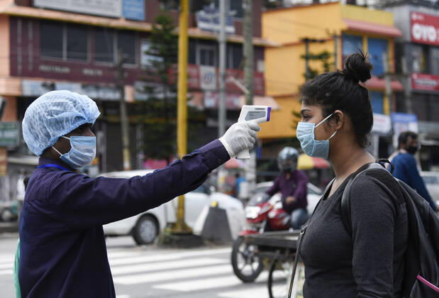 April 25, 2020, Guwahati, Assam, India: Health worker thermal screening a girl as she is arrived at a bus stop to catch a bus, state authorities eased restrictions on inter-district travel for three days, during the nationwide lockdown to curb the spread of coronavirus, in Guwahati. Guwahati India - ZUMAt232 20200425_zip_t232_015 Copyright: xDavidxTalukdarx