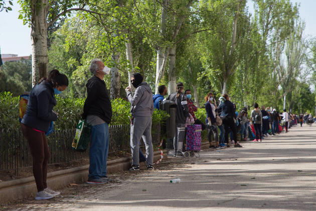Spain: Food distribution due to Covid-19 crisis A large queue of people in the surroundings of the Aluche Neighbors Association wait while they guard the safety space between them to receive food. Madrid Madrid Spain Copyright: FerxCapdeponxArroyo