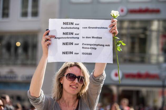 April 25, 2020, Munich, Bavaria, Germany: A demonstrator at a conspiracy theorist demo in Munich, Germany holds a sign opposing vaccines, alleged ID chips in vaccines, ID2020, and other topics. Organized in Telegram chats by conspiratorial â€oeQuerfront†(cross-front) groups, the city of Munich, Germany saw numerous anti-state â€oeCorona Parties†as under mottos such as â€oeDemonstration fuer die Erhaltung der Grundrechte†(Demonstration for the Upholding of Basic Rights) and â€oeFuer unsere Freiheit, unsere Grundrechte und unsere Selbstbestimmung†(Demonstration for our Freedom, Basic Rights, and Self-Determination). Numerous right-extremists, Verfassungsschutz-monitored figures, QAnon fans, and AfD politicians were in attendance. The groups are of the belief that the anti-Coronavirus measures are p - ZUMAb160 20200425_zbp_b160_025 Copyright: xSachellexBabbarx