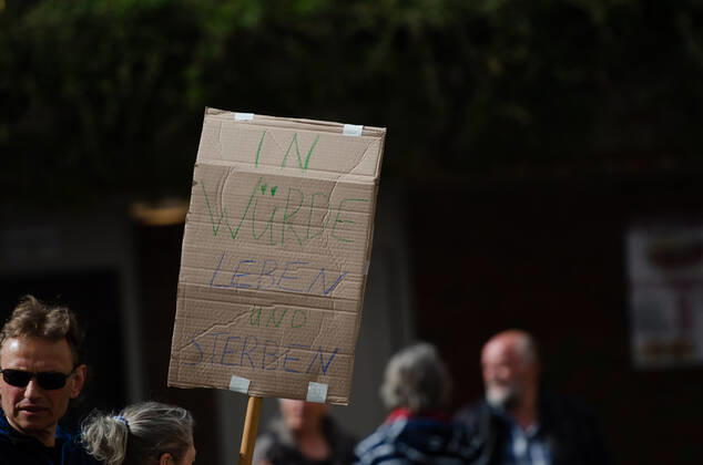 Lockdown beenden sofort! - Demonstration auf dem Südermarkt von Flensburg Die Kommunikationsstelle Demokratischer Widerstand veranstaltet eine Demonstration am 25.04.2020 in Flensburg auf dem Südermarkt, Innenstadt; Demontrant hält Transparent mit der Aufschrift In Würde leben und sterben
