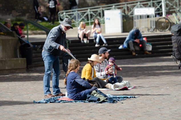 Lockdown beenden sofort! - Demonstration auf dem Südermarkt von Flensburg Die Kommunikationsstelle Demokratischer Widerstand veranstaltet eine Demonstration am 25.04.2020 in Flensburg auf dem Südermarkt, Innenstadt; hier: Demonstranten sitzen auf dem Boden des Südermarktes mit Decke und Transparenten vor sich, eine Person verteilt Zettel