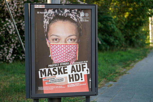 Die Stadt Heidelberg bittet die Heidelberger Bevölkerung mit einer Plakataktion, sich ab Montag, den 27. April 2020, an die dann geltende Maskenpflicht zu halten, um sich und andere vor einer Ansteckung mit dem Coronavirus zu schützen, das Plakat zeigt eine freundliche Frau mit Mundschutz und Kopftuch und der Aufschrift: Protect Others, Maske auf, HD!, Plakatmotiv: Katharina Wodajo (Betreiberin Cefe Leitstelle), Plakate, Hinweis, Hinweistafel, Hinweisschild, Corona, Schutz, Selbstschutz, Verordnung, behördliche Anweisung, Auflage, Gebot, Verhaltensregel, Maßnahme, Symbolfoto, Symbolbild, Symbol, 25.04.2020, Heidelberg (Deutschland), Feature, Coronavirus, Impressionen aus Heidelberg