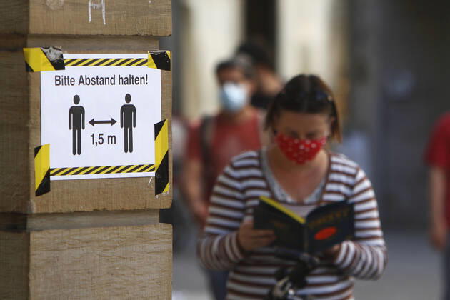 Sicherheitsmaßnahmen zur Abstandswahrung in der Innenstadt von Karlsruhe: Plakat mit Aufschrift bitte Abstand von 1,50 Metern halten und eine lesende Frau mit Atemschutzmaske an einem Buchladen, Baden Württemberg, Deutschland